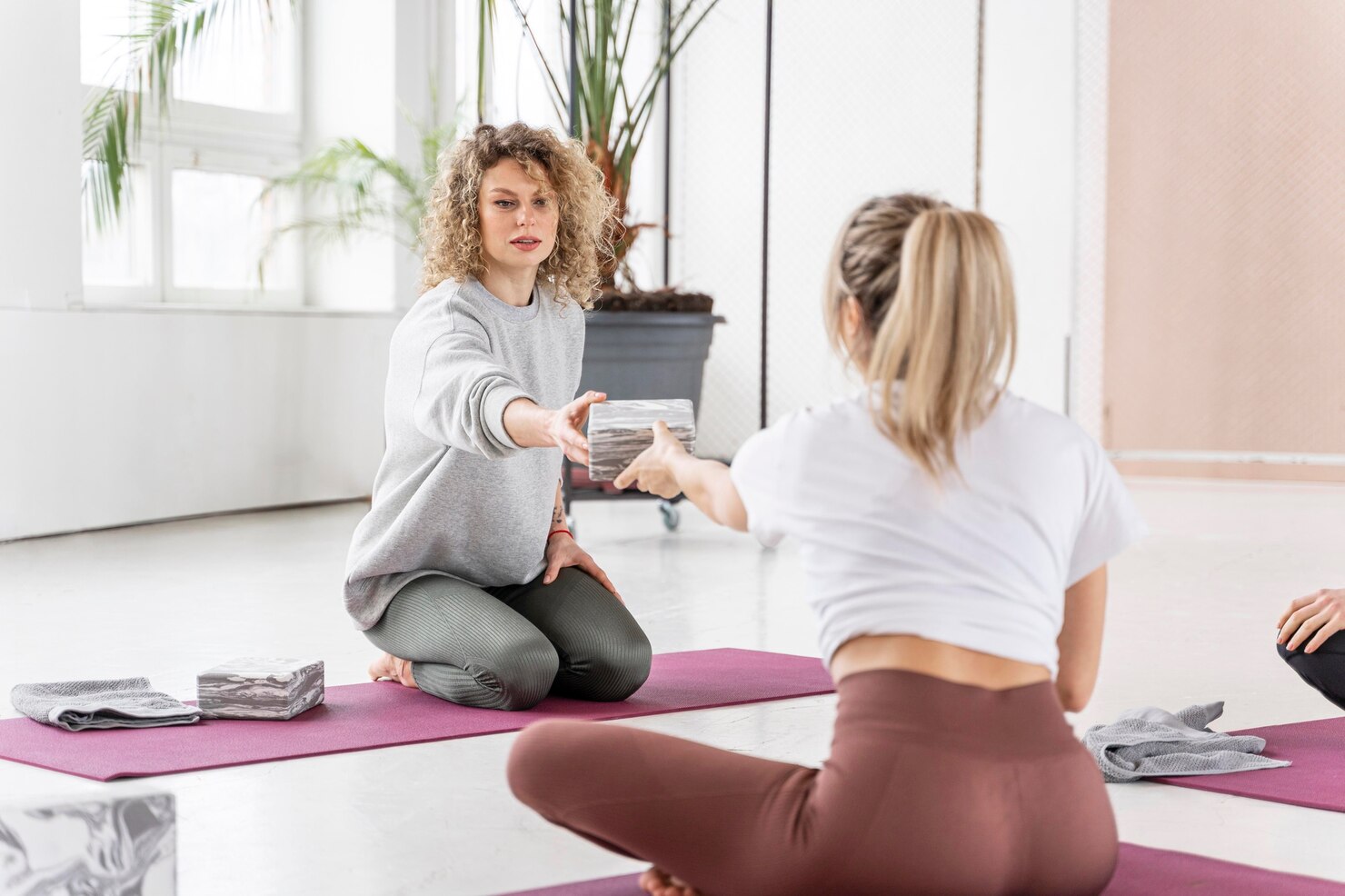 Clase de yoga con instructor guiando la práctica en un estudio luminoso